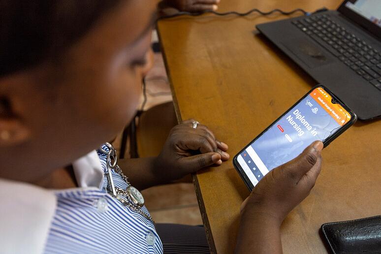 Een vrouw studeert via haar mobiele telefoon