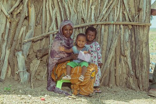 Een vrouw in Ethopie zit met haar kinderen voor haar huis